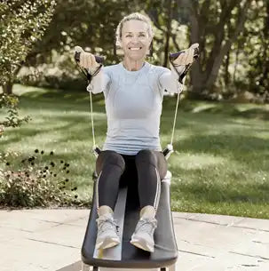 A woman outdoors exercising on a Total Gym.