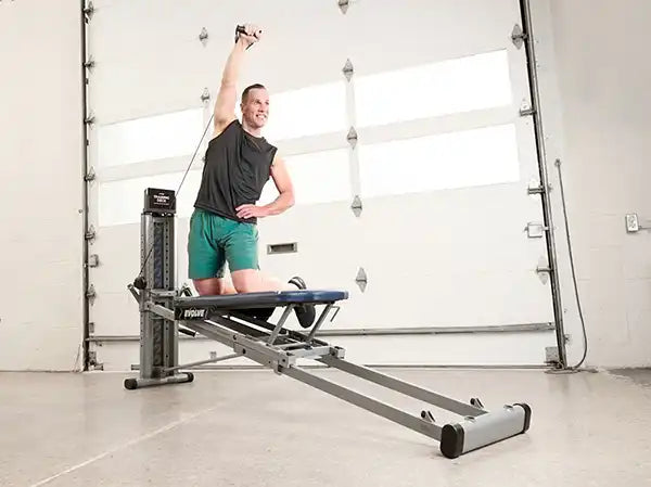 Woman working out on a Total Gym EVOLVE home gym in a living room